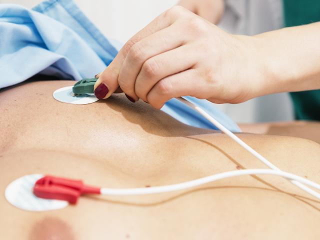 Herzinsuffizienz diagnostizieren – Ärztin positioniert Elektroden für EKG auf Patientenbrust